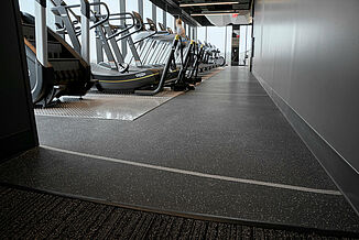 Cardio Area in Corporate Wellness Center with REGUPOL aktiv rolled Flooring A row of cardio equipment, including treadmills and elliptical trainers, in a corporate fitness center.