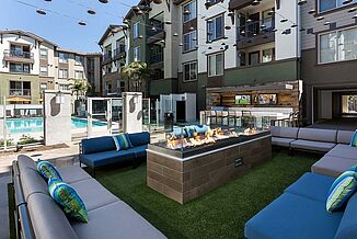 Outside patio area with a variety of couches, a fire pit and a view of the swimming pool at the Avalon Bay Communities.