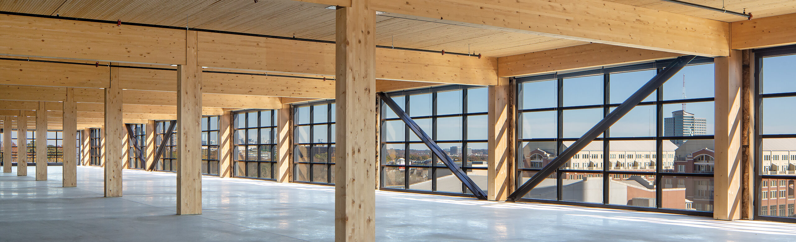 Mass Timber Construction View of a newly constructed building, featuring mass timber construction and concrete flors, overlooking a city skyline.