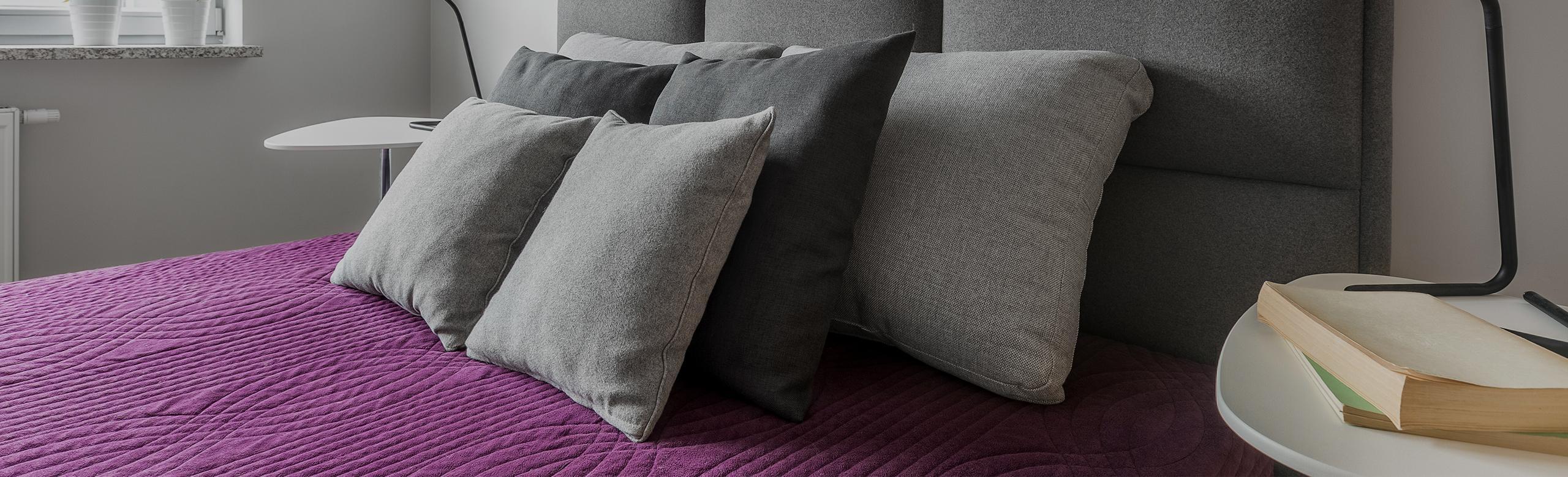 REGUPOL acoustics - Hotels A bed in a hotel room that features REGUPOL acoustics for noise absorption.When choosing city hotels, a central location, amenities, and quiet, clean rooms are important. Our REGUPOL sonus range offers noise reduction solutions for construction needs.