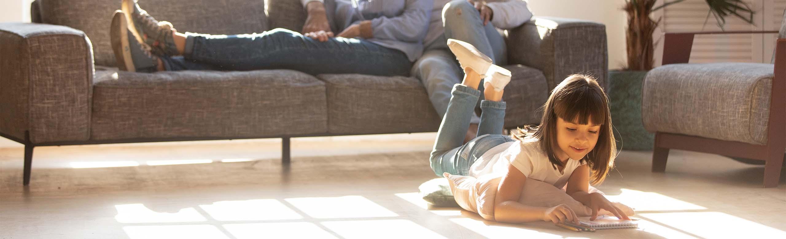 REGUPOL sonusclips - Flooring A girl lies on floors that feature REGUPOL sonusclips, providing reduced sound transmission through interior walls and ceilings.